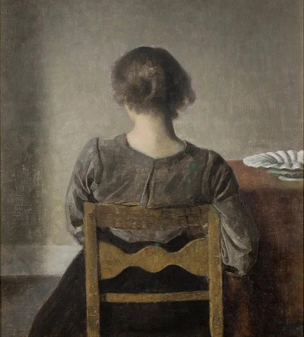 A woman seen from behind, seated at rest in a grey room