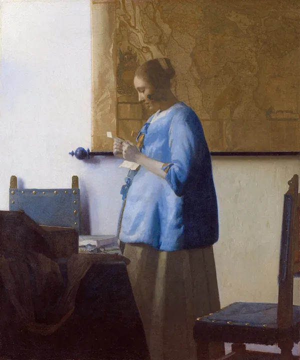 A woman in blue stands by a window reading a letter
